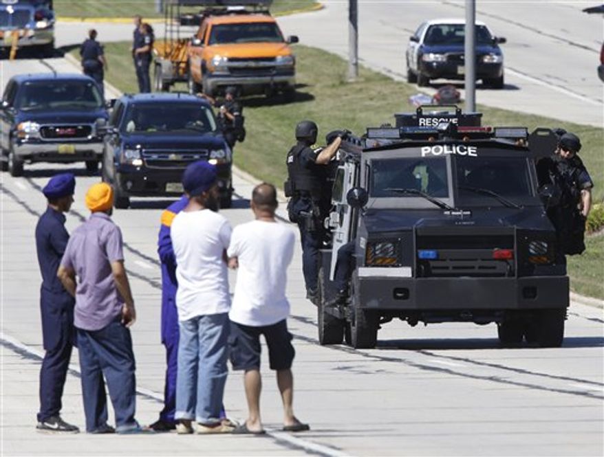 People watch police personnel outside the Sikh Temple in Oak Creek, Wis., where a shooting took place on Sunday, Aug 5, 2012. (AP Photo/Jeffrey Phelps)