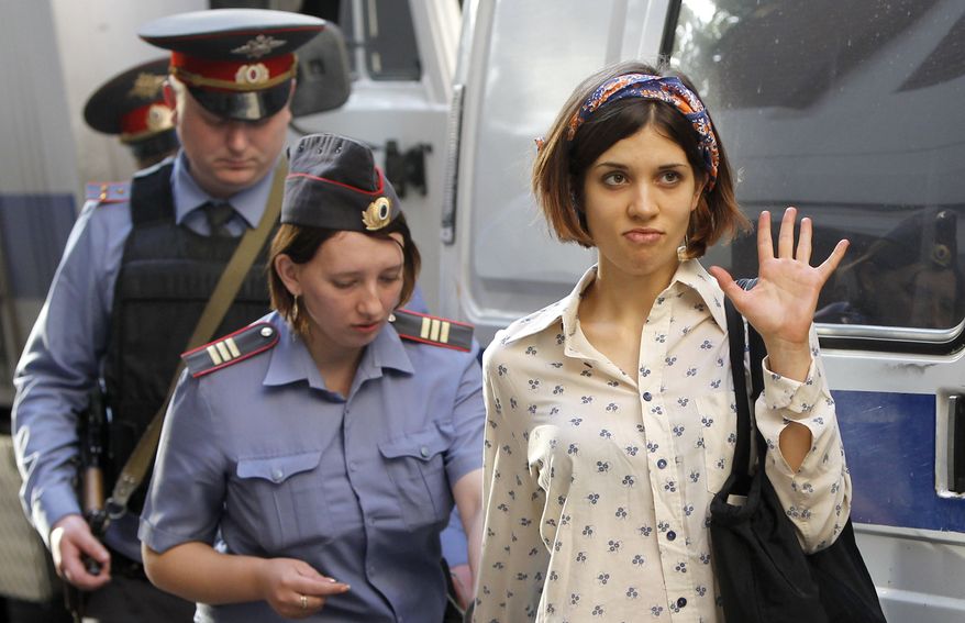 ** FILE ** Nadezhda Tolokonnikova (right), a member of feminist punk band Pussy Riot, is escorted on Wednesday, Aug. 1, 2012, to a police van in Moscow. (Associated Press)