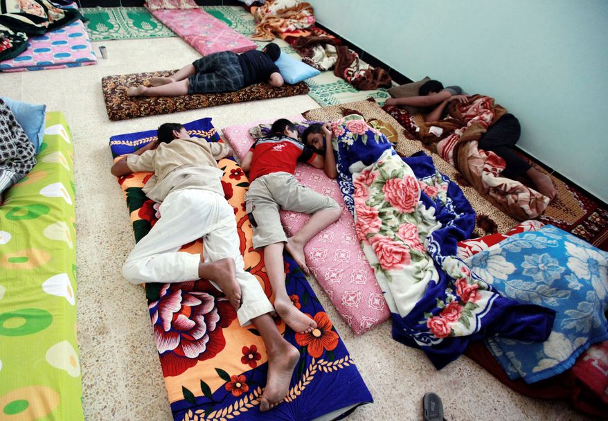 Syrian refugees rest as they cross the border by the Iraqi town of Qaim on Tuesday. In Baghdad, at least 22,300 Iraqis who had fled to Syria several years ago have streamed home in the past three weeks. (Associated Press)