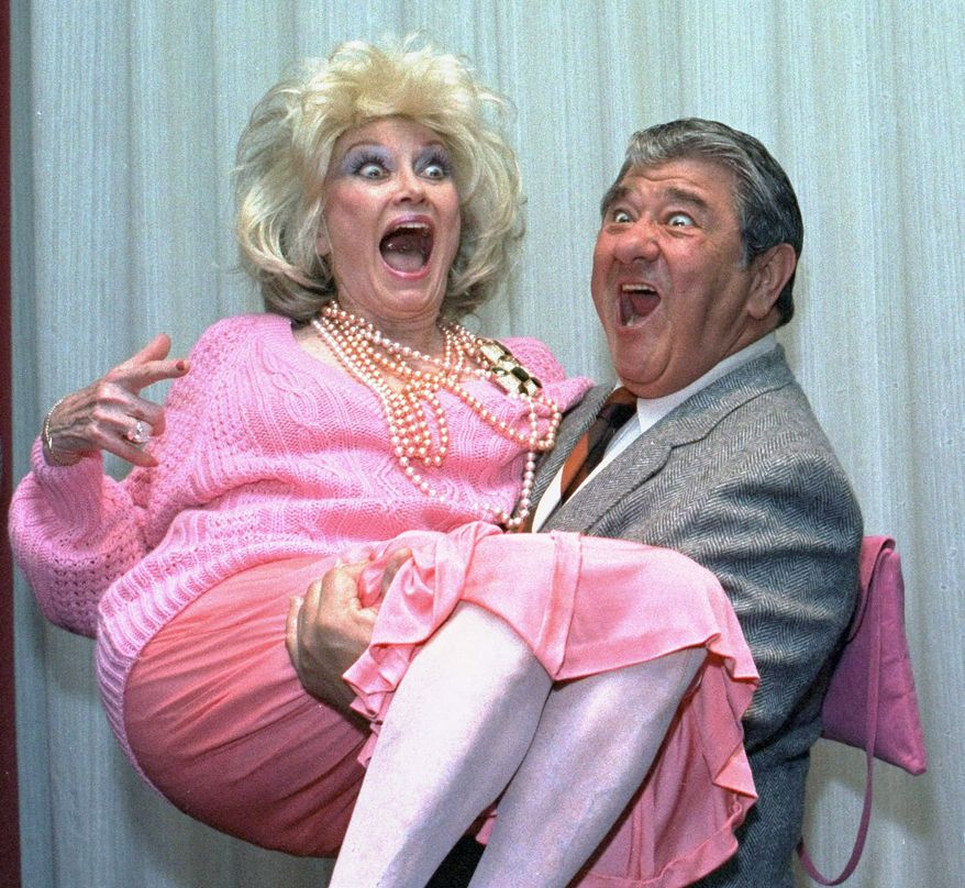 **FILE** Comedian Phyllis Diller gets a lift from emcee Buddy Hackett prior to the celebrity stag luncheon roast at the New York Friars Club in New York City on Oct. 9, 1985. (Associated Press)