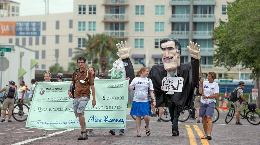 Members of a Florida consumer activism group Sunday march down the streets of Tampa, Fla., with a giant Mitt Romney puppet. Republican National Convention protesters, many of whom have camped outdoors, said the wind and rain expected Monday from Tropical Storm Isaac would not deter their plans for the week. Tampa officials warned that if safety becomes a concern, people will be ordered off the streets. (Andrew S. Geraci/The Washington Times)