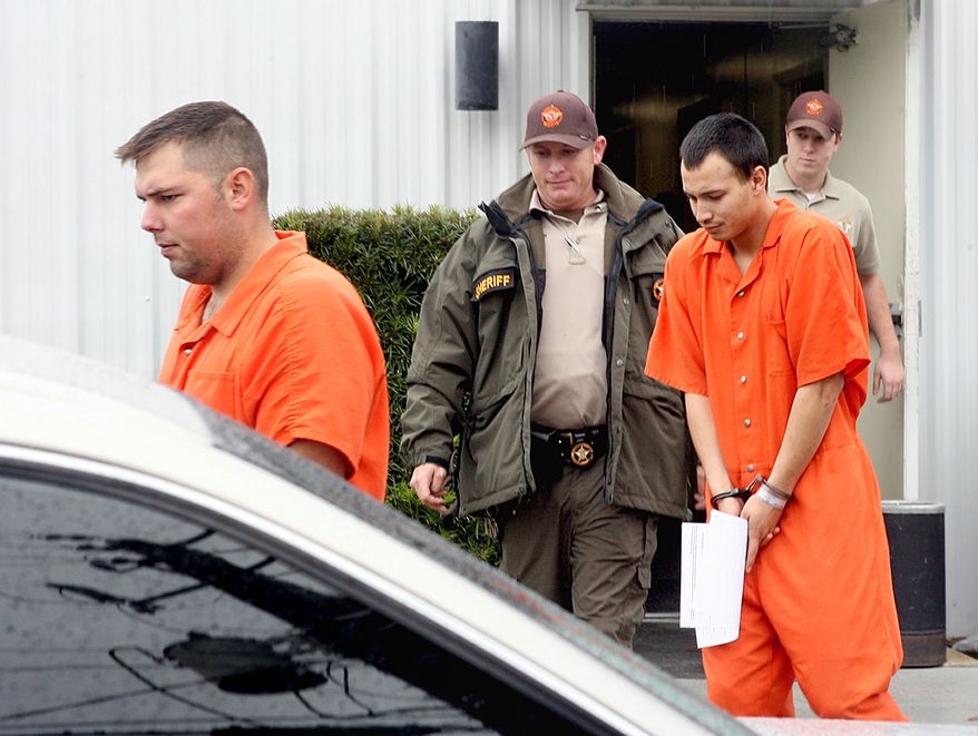 **FILE** U.S. Army Sgt. Anthony Peden (left), 25, and Pvt. Isaac Aguigui, 19, are led away in handcuffs Dec. 12, 2011, after appearing before a magistrate judge at the Long County Sheriff's Office in Ludowici, Ga. Peden and Aguigui are two of four soldiers in Georgia charged with killing a former comrade and his girlfriend to protect an anarchist militia group they formed that stockpiled assault weapons and plotted a range of anti-government attacks. (Associated Press)