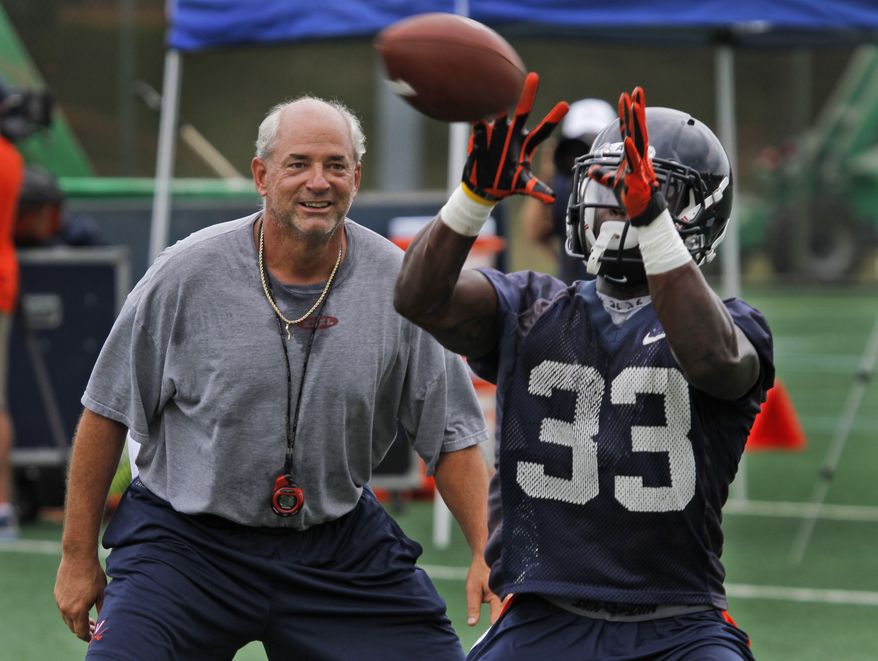 Virginia defensive coordinator, Jim Reid, left, plays defender as tailback, Perry Jones (33) hauls in a pass during practice in Charlottesville, Va., Monday, Aug. 6, 2012. ( AP Photo/Steve Helber)