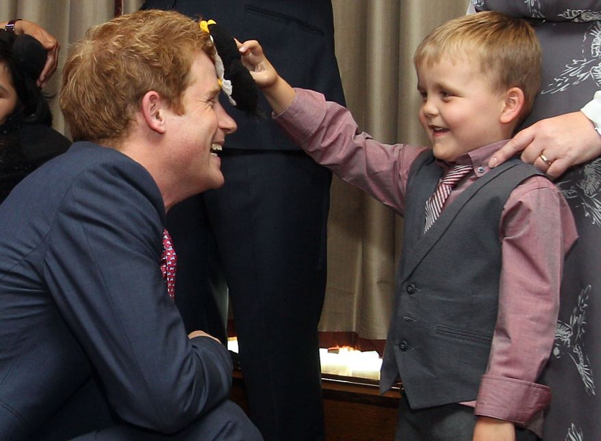 Britain's Prince Harry talks with Alex Logan (right), who puts a toy penguin against Harry's head, at the WellChild awards ceremony at the InterContinental Park Lane Hotel in London on Monday, Sept. 3, 2012. (AP Photo/Lewis Whyld)