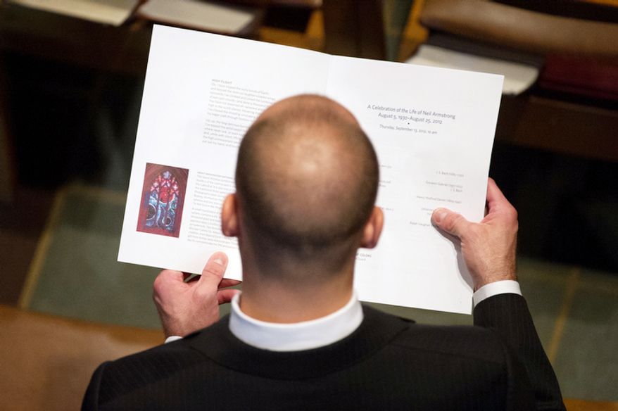 An attendee looks at the program booklet for the memorial service for Neil Armstrong at the National Cathedral. (Andrew Harnik/The Washington Times)