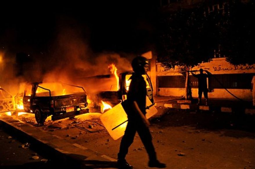 A riot policeman passes a burning vehicle during clashes outside the U.S. embassy in Cairo early Thursday, Sept. 13, 2012, as part of widespread anger across the Muslim world about a film ridiculing Islam's Prophet Muhammad. (Associated Press)