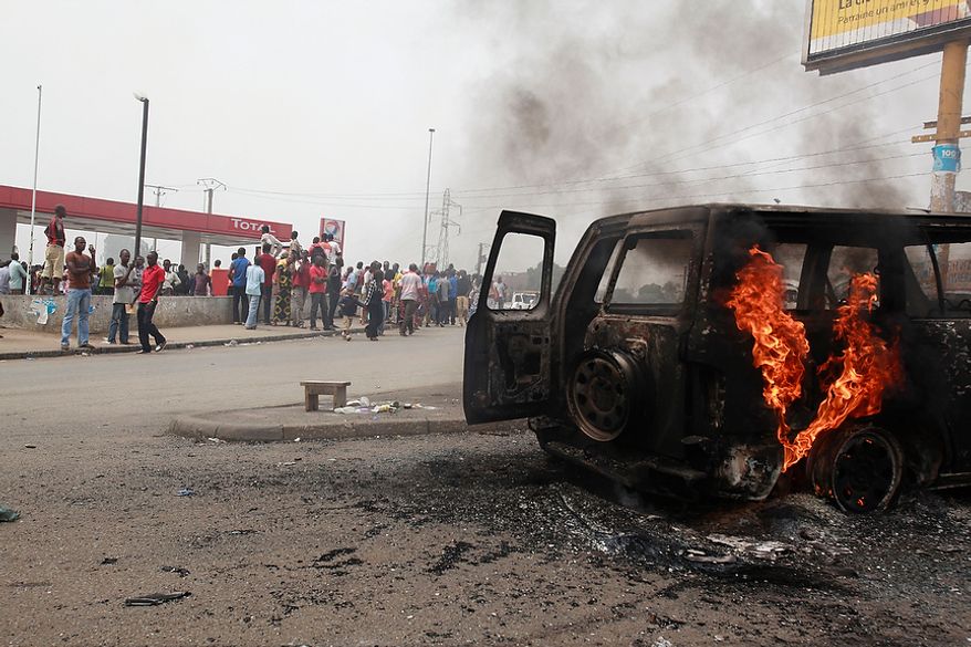 ** FILE ** Residents look on as a U.N. vehicle, set on fire by militant student supporters of Ivorian strongman Laurent Gbagbo, burns in the Riviera 2 neighborhood of Abidjan, Ivory Coast, on Thursday, Jan. 13, 2011. (AP Photo/Rebecca Blackwell)