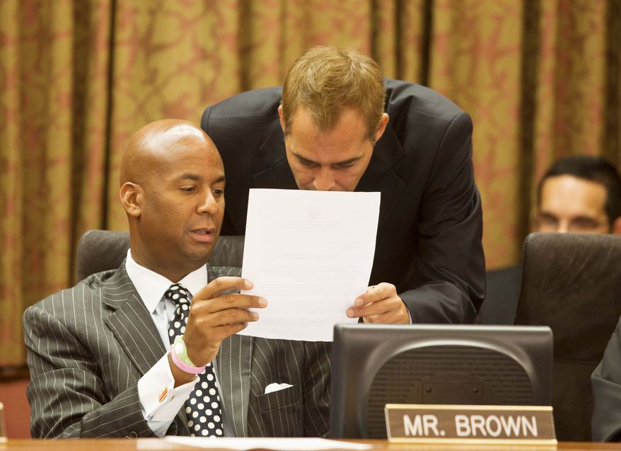 D.C. Council member Michael A. Brown confers with a staffer Wednesday during a council meeting. Mr. Brown has introduced a bill that calls for exploring public financing of political campaigns in the city. (Craig Bisacre/The Washington Times)