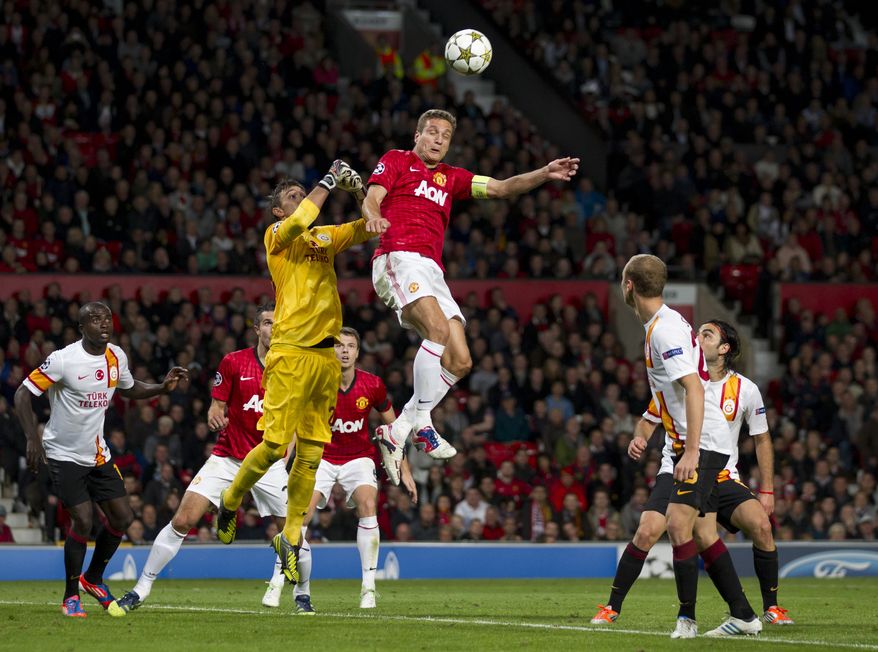 Manchester United's Nemanja Vidic, jumps for the ball against Galatasaray's goalkeeper Fernando Musera during their Champions Graoup H soccer match at Old Trafford Stadium, Manchester, England, Wednesday, Sept. 19, 2012. (AP Photo/Jon Super)