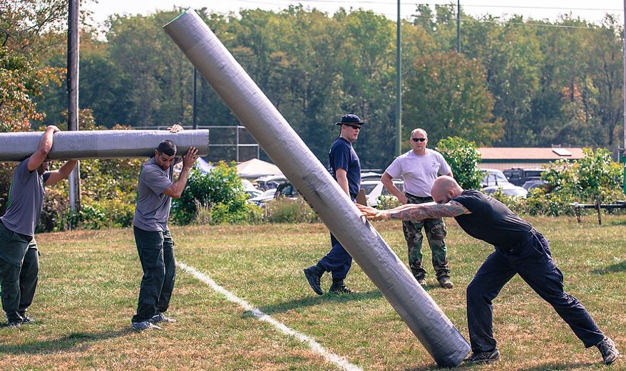 Officer Matt Harbison, assigned to Metro Transit in Washington D.C., flips a log weighing hundreds of pounds across the finish line at the Iron Team Endurance Competition in Laurel, MD., Wednesday, September 26, 2012. The competition is hosted by the Prince George's County Police where teams from all over the east coast, including the Marines, compete in a grueling physical endurance challenge.(Andrew S. Geraci/The Washington Times)