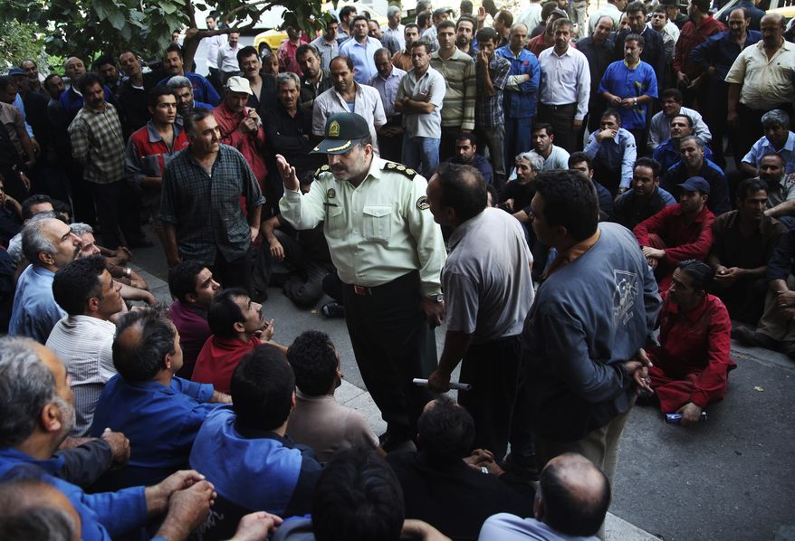 **FILE** A police colonel (center) talks with a group of Iranian workers Aug. 14, 2012, during their protest in front of the Industrial Ministry building in Tehran to demand their delayed salaries. (Associated Press)