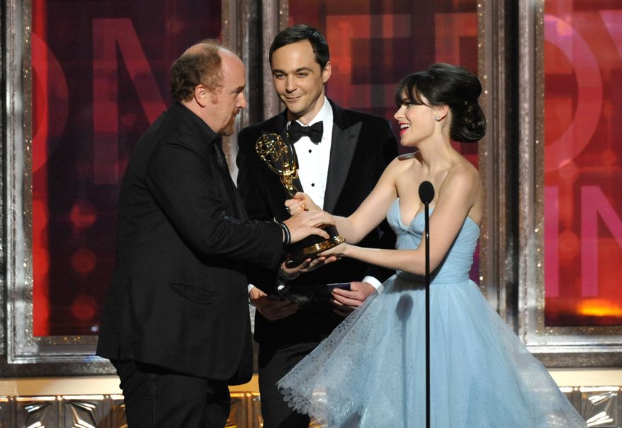 Louis C.K. (left) receives the Emmy for outstanding writing in a comedy series from Jim Parsons and Zooey Deschanel at the 64th Primetime Emmy Awards on Sunday, Sept. 23, 2012, in Los Angeles. (John Shearer/Invision/AP)