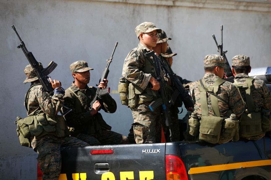 **FILE** Soldiers stand guard Dec. 21, 2010, while police raid a home in Coban, Guatemala. In December 2010, the Guatemalan military declared a month long state of siege in Alta Verapaz in hopes of reclaiming cities that have been taken over by Mexico's Zetas drug gang. Guatemalan authorities say they have begun to see new and disturbing evidence of an alliance between the Mara Salvatrucha street gang and the Zetas drug cartel, one of the most feared criminal organizations in Latin America, a deal with the potential to further undermine the U.S.-backed effort to fight violent crime and narcotics trafficking in the region. (Associated Press)