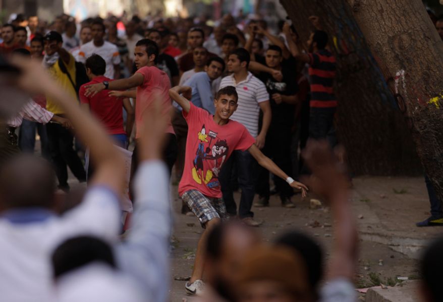 A protester throws a stone after scuffles broke out between groups of several hundred protesters in Tahrir square when chants against the new Islamist president angered some in the crowd in Cairo, Egypt, Friday, Oct. 12, 2012. The scuffles between supporters and opponents of President Mohammed Morsi reflect deep political divisions among the countryís 82 million people, more than a year after the popular uprising that toppled Hosni Mubarak. (AP Photo/Khalil Hamra)