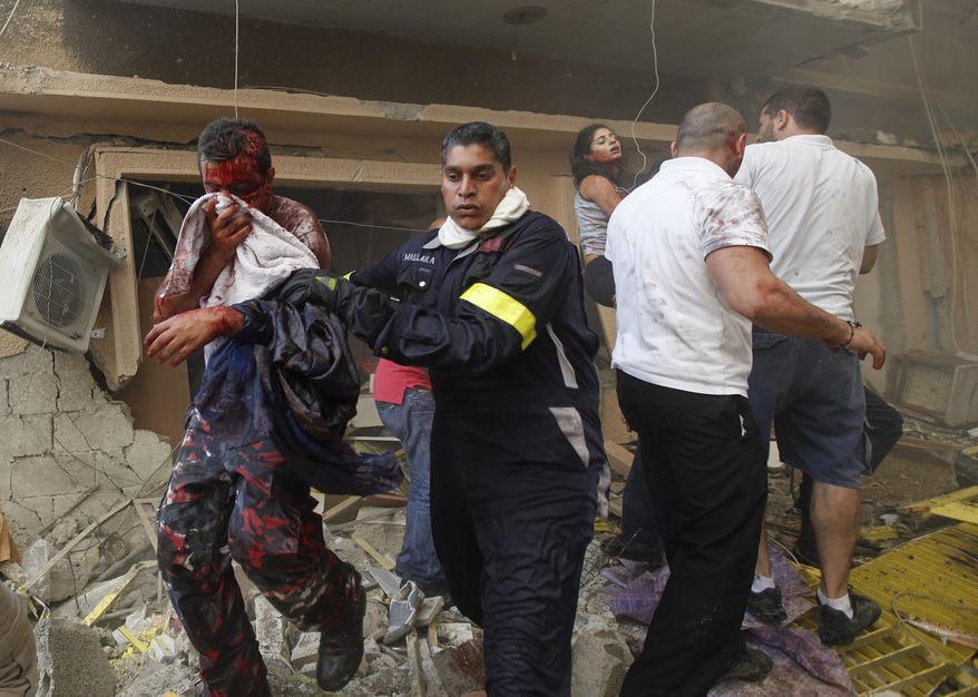 A Lebanese rescue worker (center) helps an injured man at the scene of an car bomb explosion Oct. 19, 2012, in the mostly Christian neighborhood of Achrafiyeh in Beirut. (Associated Press)