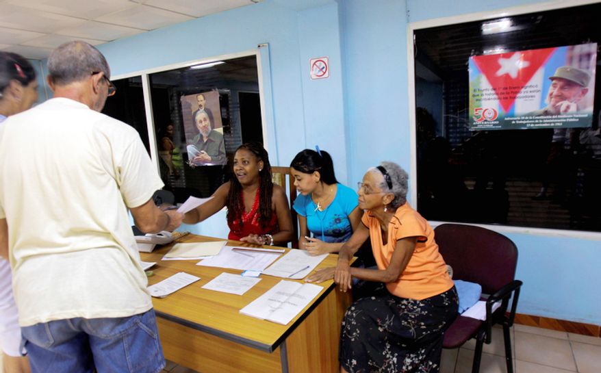 Under pictures of Cuba's leader Fidel Castro, people cast their ballots at a polling station in Havana, Sunday Oct. 21, 2012. Cubans are going to the polls Sunday to vote in municipal elections. (AP Photo/Ismael Francisco/Cubadebate)
