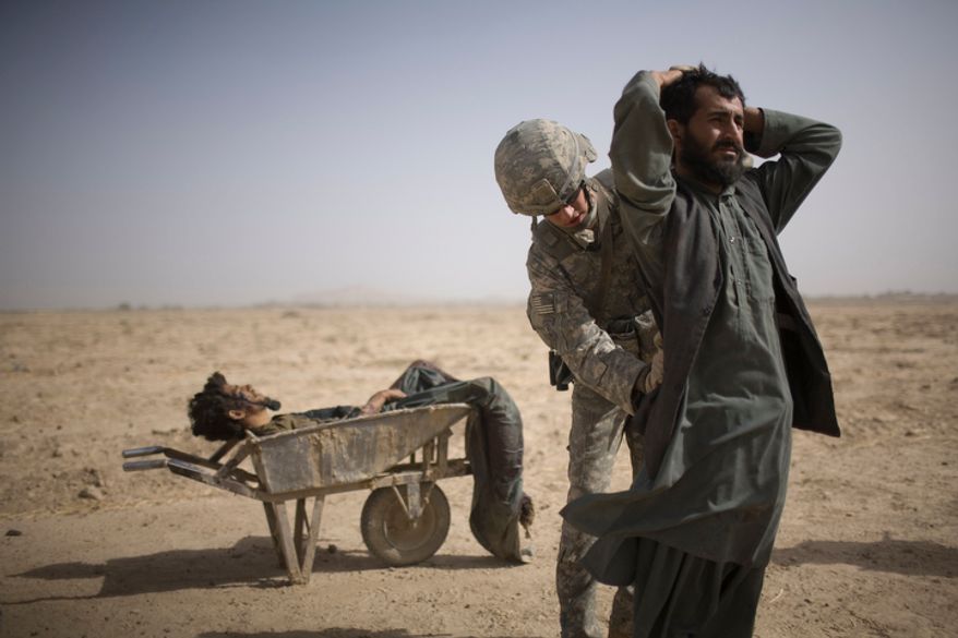 In this photo taken Sunday, Oct. 10, 2010, a US Army soldier from Scout Platoon 502 Infantry Regiment, 101st Airborne Division searches an associate of a suspected Taliban IED placer, seen in a wheelbarrow, who was killed in a coalition missile strike in Zhari district, Kandahar province. The Scouts' mission was to support roadside bomb clearance efforts in the militant stronghold, the latest days-long phase of Operation Dragon Strike. (AP Photo/Rodrigo Abd)