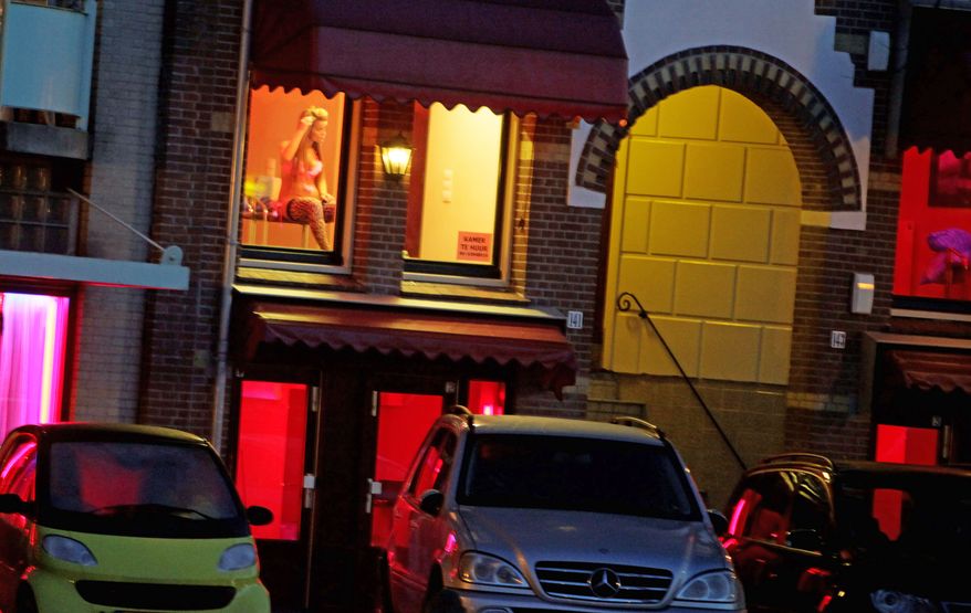 ** FILE ** A prostitute advertises in a window in Amsterdam's Red Light District. (Associated Press)