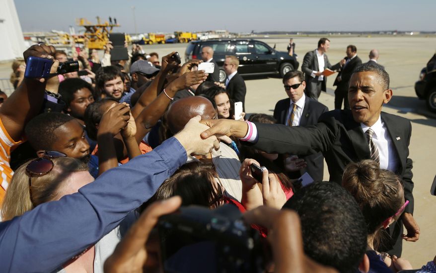 President Obama reaches over to greets supporters on the tarmac upon his arrival Oct. 25, 2012, on Air Force One at Richmond International Airport in Richmond, Va. (Associated Press)