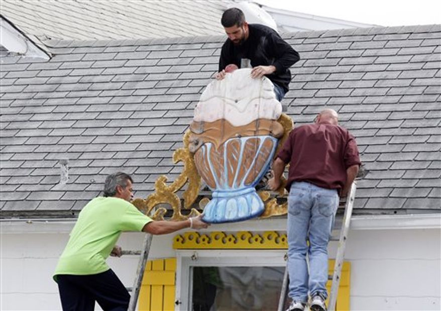 Jerry Velez, top, Richard Caguilat, left, and William Disburger, right, remove a large sign from the Sea Shell Ice Cream shop in Wildwood, N.J., Saturday, Oct. 27, 2012, in preparation for Hurricane Sandy. From the lowest lying areas of the Jersey shore, where residents were already being encouraged to leave, to the state's northern highlands, where sandbags were being filled and cars moved into parking lots on high ground, New Jersey began preparing in earnest for Hurricane Sandy. (AP Photo/Mel Evans)