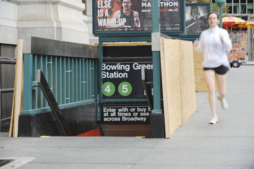 Plywood covers part of the entrance to Bowling Green Station in Battery Park as storm preparation is done in New York. (AP Photo/ Louis Lanzano)