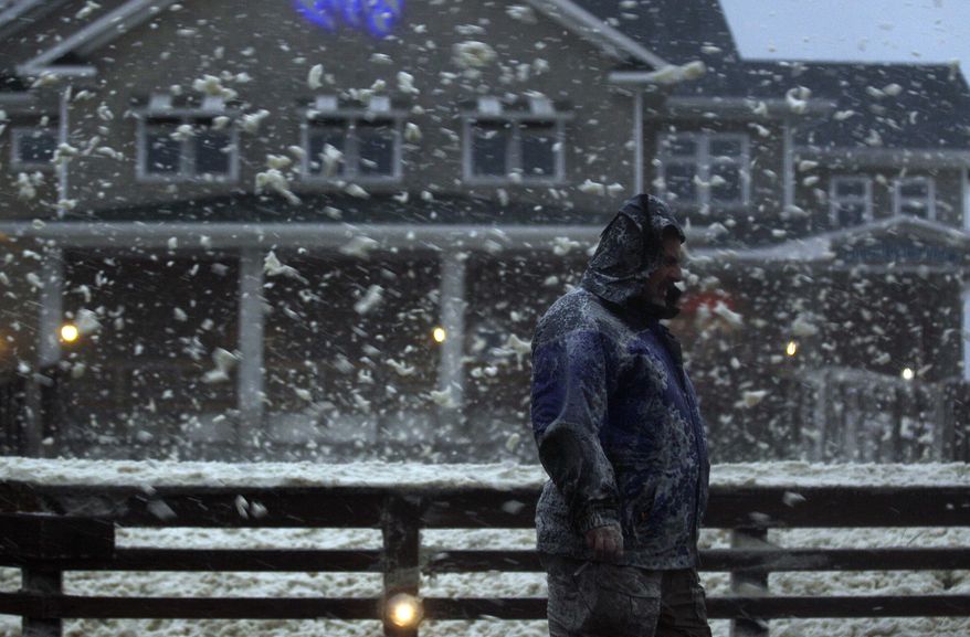 High winds blow sea foam into the air as a pedestrian crosses Jeanette's Pier in Nags Head, N.C., on Sunday, Oct. 28, 2012, as wind and rain from Hurricane Sandy move into the area. (AP Photo/Gerry Broome)