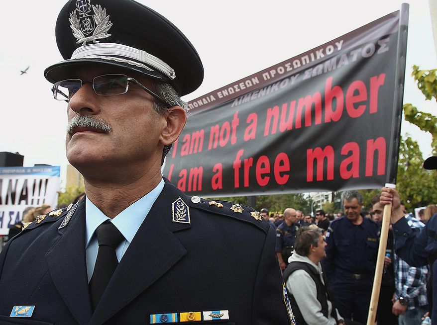 A Greek police officer stands in front of a banner during a protest in central Athens on Thursday, Nov. 1, 2012. More than a thousand protesting officers from the police, coast guard and fire department joined a rally in Athens to demonstrate against government cuts, in the latest protest ahead of a planned two-day general strike next week. (AP Photo/Thanassis Stavrakis)