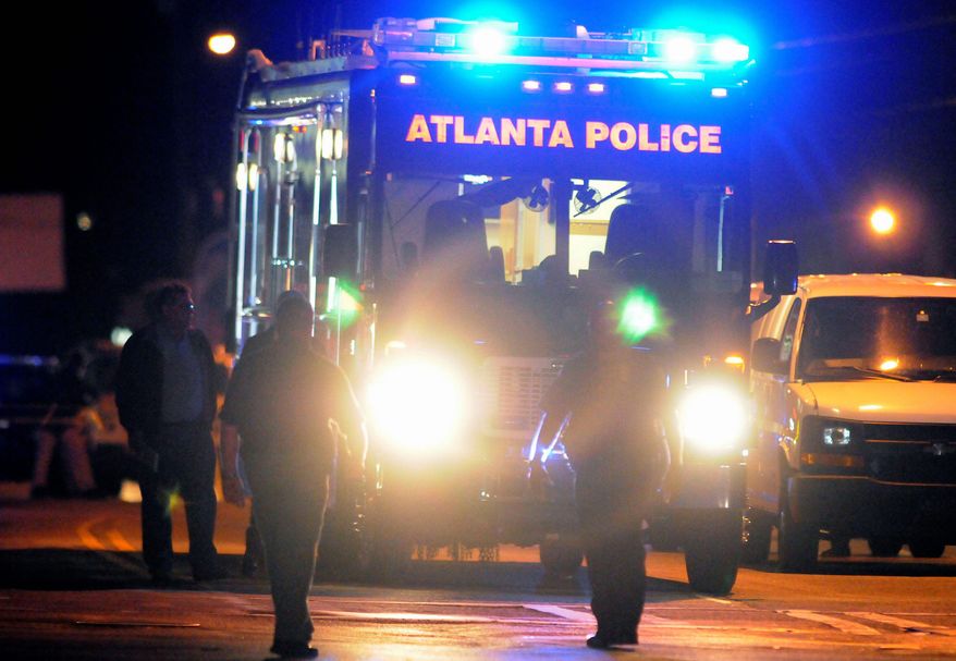 Law enforcement personnel early Sunday examine the scene of an Atlanta Police Department helicopter crash that killed two officers. The subject of their search, a 9-year-old boy who had run away from home, turned up hours later. (Associated Press)