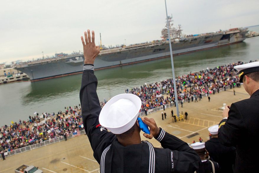 Petty Officer 3rd class, Joseph Mustafa, left, waves his family members on the deck of USS Enterprise as it docks at the Pier 12 next to USS Abraham Lincoln during its final homecoming. The Enterprise, the world's first nuclear-powered aircraft carrier ended its remarkable career at sea on Sunday when it pulled into its home port for the final time after participating in every major conflict since the Cuban Missile Crisis of 1962. (AP Photo/The Virginian-Pilot, Hyunsoo Leo Kim)