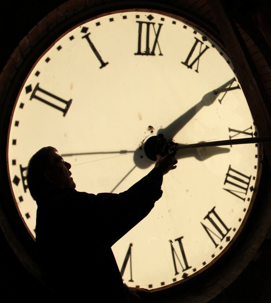 ** FILE ** Custodian Ray Keen checks the clock face after changing the time on the 97-year-old clock atop the Clay County Courthouse on Nov. 6, 2010, in Clay Center, Kan. (AP Photo/Charlie Riedel)