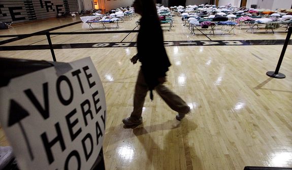 A person walks through a makeshift shelter in a gymnasium at Toms River East High School on the way to vote on Tuesday, Nov. 6, 2012, in Toms River, N.J. Voter turnout was heavy in several storm-ravaged Jersey shore towns, with many voters expressing relief and even elation at being able to vote at all, considering the devastation. (AP Photo/Mel Evans)