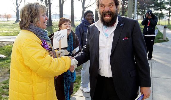 Indiana gubernatorial candidate Libertarian Rupert Boneham laughs as he's told by poling place volunteer Carol Mapier that he "has a great body" as he greeted voters outside a poling place in Indianapolis, Tuesday, Nov. 6, 2012. Boneham faces Democrat John Gregg and Republican Mike Pence in the gubernatorial race. Boneham was a contestant on the reality show Survivor. (AP Photo/Michael Conroy)