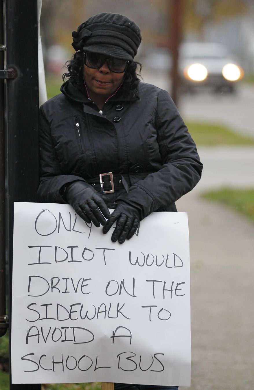 Shena Hardin holds up a sign in Cleveland on Nov. 13, 2012, to serve a highly public sentence for driving on a sidewalk to avoid a Cleveland school bus that was unloading children. (Associated Press)