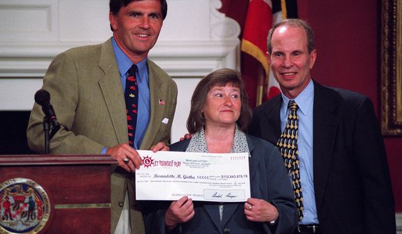 **FILE** Bernadette "Bernie" Gietka (center), winner of the $112 million interstate Mega Millions lottery, holds her winnings check at the Maryland State House in Annapolis with Maryland Gov. Robert L. Erlich (left) and Maryland Lottery Agency Director Buddy Roogow on July 2, 2003. (Caroling Lee/The Washington Times)