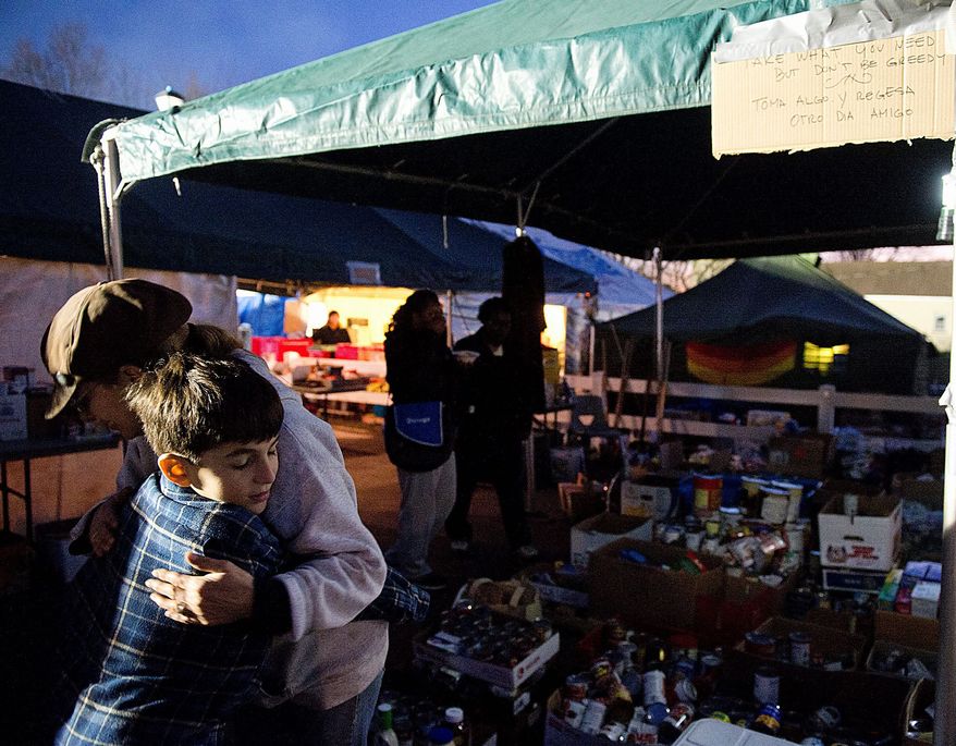 Andrew hugs volunteer Amy Sahlin at a relief station in Union Beach, N.J. on Wednesday. He and his family will volunteer at the station Thanksgiving Day. (Barbara L. Salisbury/The Washington Times)