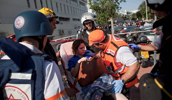 Israeli rescue workers and paramedics carry an injured woman from the site of a bombing in Tel Aviv, Israel, Wednesday, Nov. 21, 2012. A bomb ripped through an Israeli bus near the nation's military headquarters in Tel Aviv on Wednesday, wounding several people, Israeli officials said. The blast came amid a weeklong Israeli offensive against Palestinian militants in Gaza that has killed more than 130 Palestinians. (AP Photo/Oded Balilty)