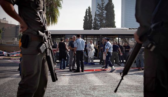 Israeli police and security personnel stand next to a destroyed bus at the site of a bombing in Tel Aviv, Israel, Wednesday, Nov. 21, 2012. A bomb ripped through an Israeli bus near the nation's military headquarters in Tel Aviv on Wednesday, wounding several people, Israeli officials said. The blast came amid a weeklong Israeli offensive against Palestinian militants in Gaza.(AP Photo/Dan Balilty)