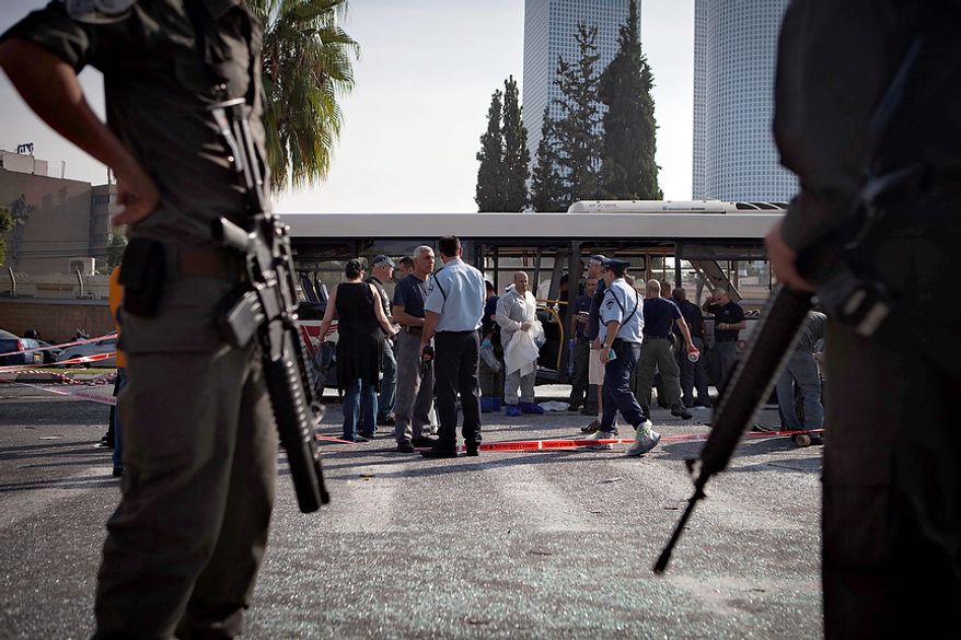 Israeli police and security personnel stand next to a destroyed bus at the site of a bombing in Tel Aviv, Israel, Wednesday, Nov. 21, 2012. A bomb ripped through an Israeli bus near the nation's military headquarters in Tel Aviv on Wednesday, wounding several people, Israeli officials said. The blast came amid a weeklong Israeli offensive against Palestinian militants in Gaza.(AP Photo/Dan Balilty)