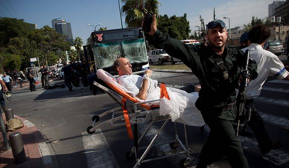 Israeli rescue workers and paramedics carry a wounded person from the site of a bombing in Tel Aviv, Israel, Wednesday, Nov. 21, 2012. A bomb ripped through an Israeli bus near the nation's military headquarters in Tel Aviv on Wednesday, wounding several people, Israeli officials said. (AP Photo/Oded Balilty)
