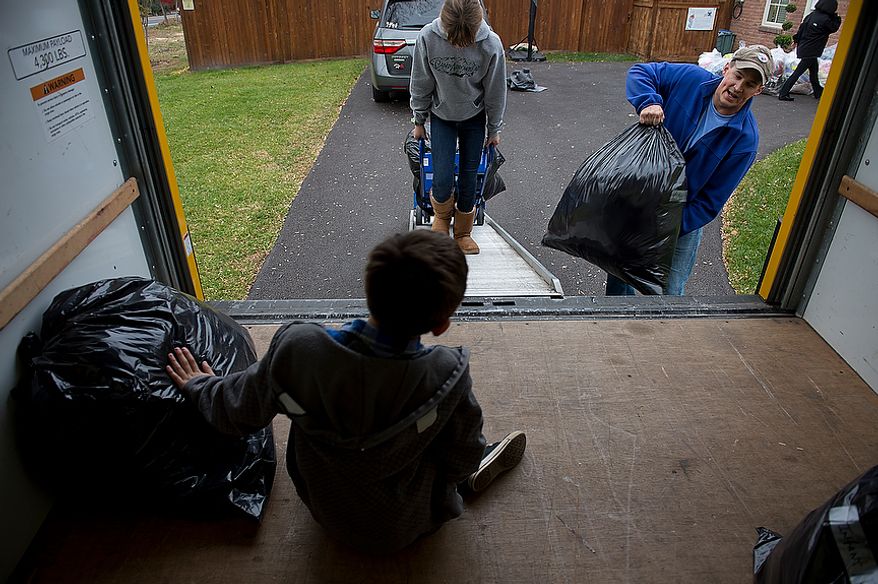 Andrew Audas, 9, bottom, sits inside the rented truck while his sister Abbi, 12, and dad Jim load bags and mom Tiffany, right, heads to the garage to pull out more stuff. The family filled their 12-foot rental truck with donations for victims of Hurricane Sandy on Tuesday, Nov. 20, 2012. They leave Wednesday morning to drive everything up to New Jersey, where they will spend Thanksgiving and the weekend volunteering. (Barbara L. Salisbury/The Washington Times)