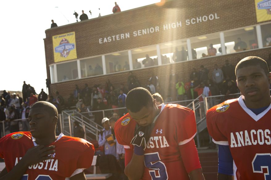 Anacostia High School's Yusuf Jones (5) bows his head during the playing of the National Anthem as they face Dunbar High School for the 43nd Annual DCIAA Turkey Bowl Varsity Football Championship at Eastern High School in Washington, D.C., Thursday, Nov. 22, 2012. This game, played between two District high school football teams is rich in tradition and always played on Thanksgiving Day, however this year's contest had a slight change in the last few days leading up to the game when Woodrow WIlson High School was disqualified because one the team's players was found to have been a resident of Maryland. Anacostia High School was chosen as an alternative. (Rod Lamkey Jr./The Washington Times)
