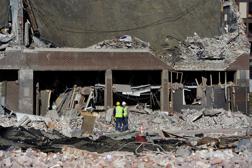 Inspectors stand in debris on Saturday, Nov. 24, 2012, at the site of a natural-gas explosion that leveled a strip club in Springfield, Mass., on Friday evening. (AP Photo/Jessica Hill)