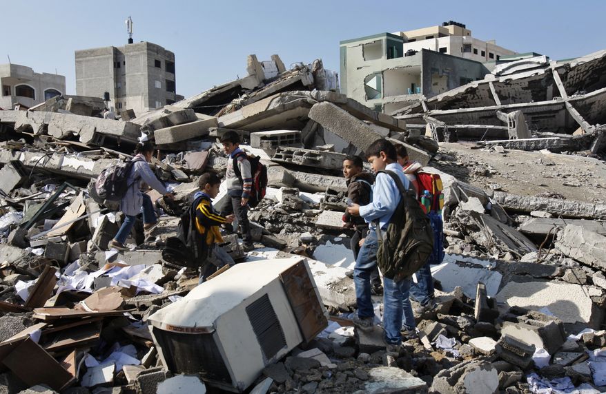 On Monday, Nov. 26, 2012, Palestinian schoolchildren walk in the rubble left days after an Israeli airstrike destroyed the Hamas Interior Ministry in Gaza City, Gaza Strip. (AP Photo/Adel Hana)