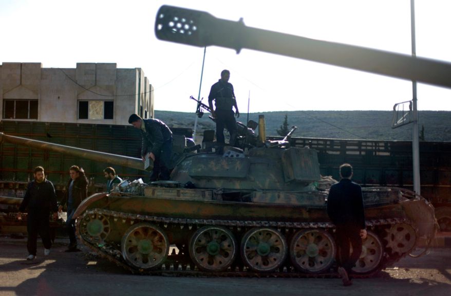 Syrian fighters check a tank they took after storming a military base in Aleppo, Syria, on Monday, Nov. 19, 2012. (AP Photo/Khalil Hamra)
