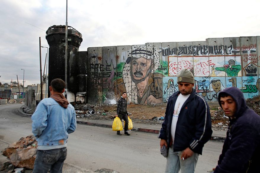 Palestinians walk past a mural on the controversial Israeli barrier depicting the late Palestinian leader Yasser Arafat, at Qalandiya checkpoint near the West Bank city of Ramallah, Tuesday, Nov. 27, 2012. Palestinian authorities on Tuesday opened Yasser Arafat's grave and foreign experts took samples from his remains as part of a long-shot attempt, eight years after the iconic leader's mysterious death, to determine whether he was poisoned, as relatives and some political successors have claimed. (AP Photo/Nasser Shiyoukhi)