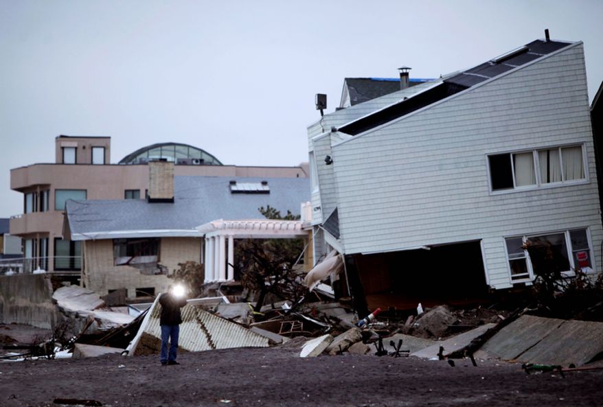 A man takes a picture of destroyed homes on the Rockaway Peninsula in the New York borough of Queens on Tuesday, Nov. 27, 2012. New York Gov. Andrew Cuomo wants huge electrical transformers hauled to upper floors of commercial buildings and the ability to shutter subways as part of a $9 billion plan to protect New York City from the next superstorm. Mr. Cuomo said that the government must take preventive measures now to avoid future loss of life and billions more in damage. (AP Photo/Seth Wenig)