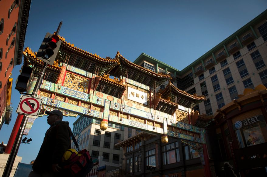 A man is silhouetted against the sunlit Chinatown arch in Chinatown near Seventh and H streets Northwest in Washington on Wednesday, Nov. 28, 2012. (The Washington Times)