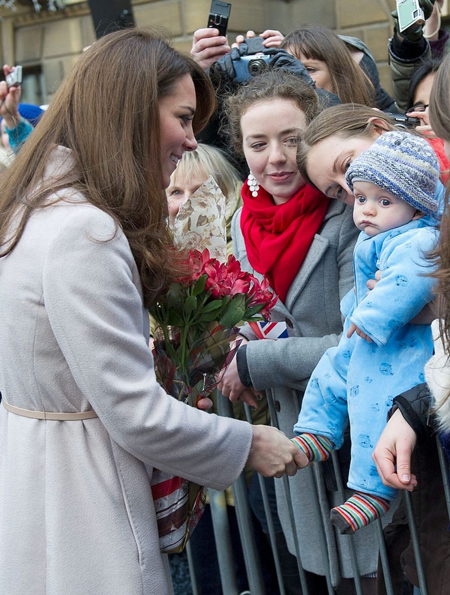 **FILE** Britain's Kate Duchess of Cambridge (left) meets Nov. 28, 2012, with a young member of the public as she arrives at the Guildhall during a visit to Cambridge, England. (Associated Press)