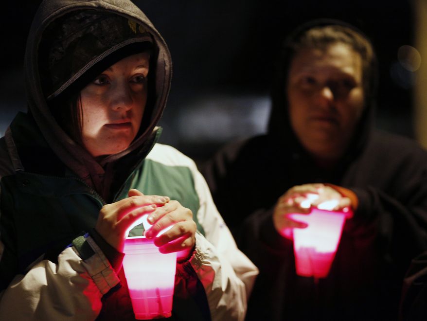 Amanda Smith holds a candle during a vigil held Dec. 5, 2012, at Meyers Lake in Evansdale, Iowa, for two young Iowa cousins who vanished five months ago while riding their bikes. (Associated Press/Waterloo Courier)