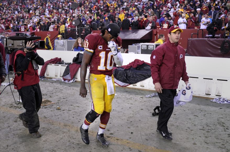 Washington Redskins quarterback Robert Griffin III (10) leaves the field with a brace on his injured right leg after defeating the Ravens 31-28 at FedEx Field, Landover, Md., Dec. 9, 2012. (Preston Keres/Special to The Washington Times)